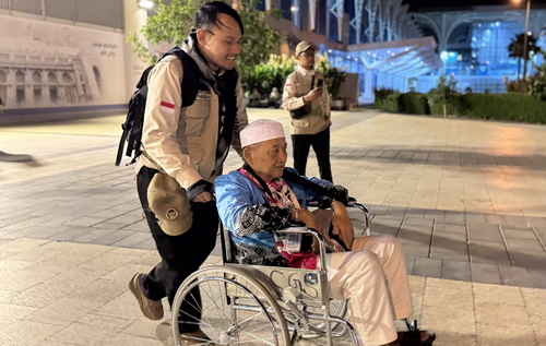 Petugas haji daerah kerja bandara membantu jemaah lansia dengan kursi roda. (ist)