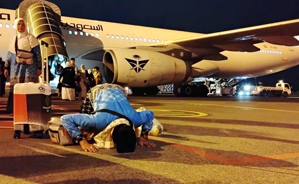Salah seorang jemaah haji kloter pertama melakukan sujud syukur usai mendarat di Bandara Juanda. (kompas)