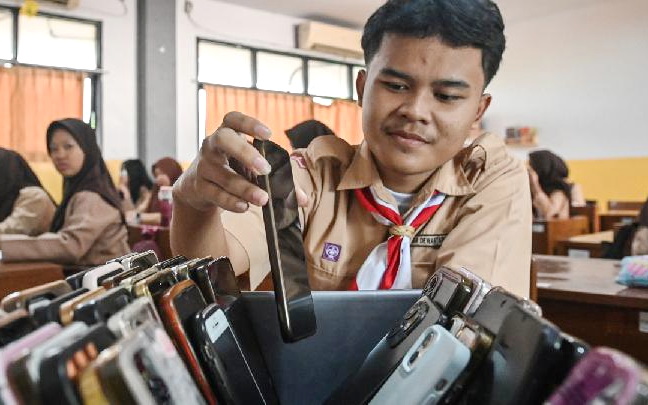 Seorang siswa sedang mengumpulkan gawai mereka saat pelajaran dimulai. (ist)